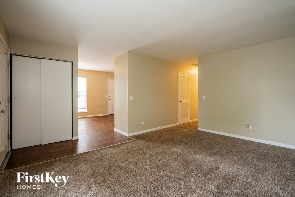 A spacious room with a carpeted floor and a sliding door.