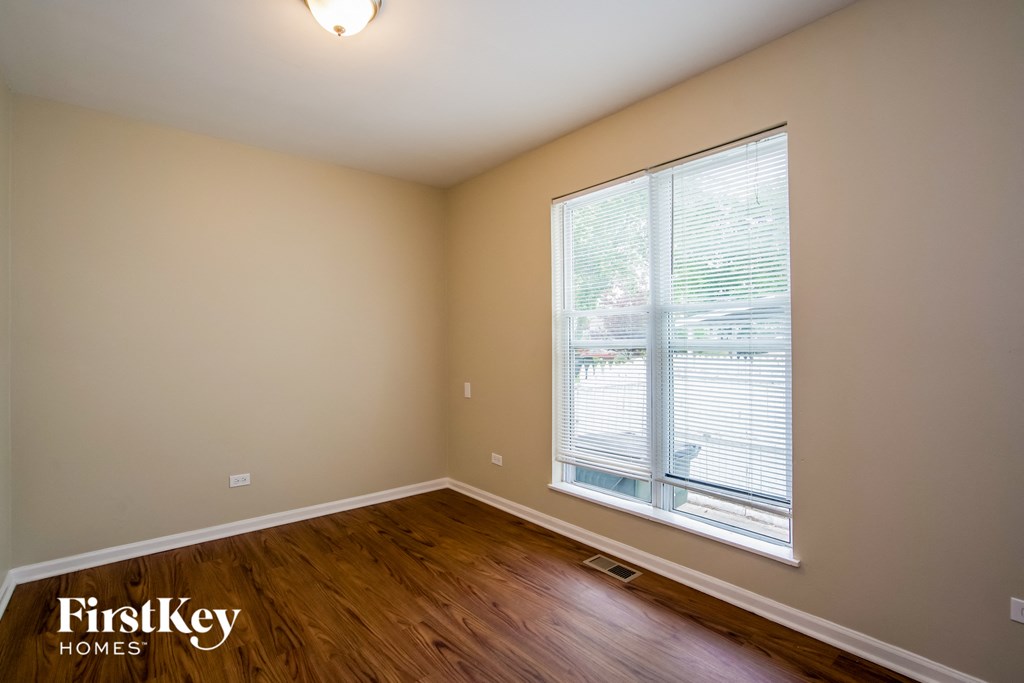 A room with wooden floors and a window with blinds.