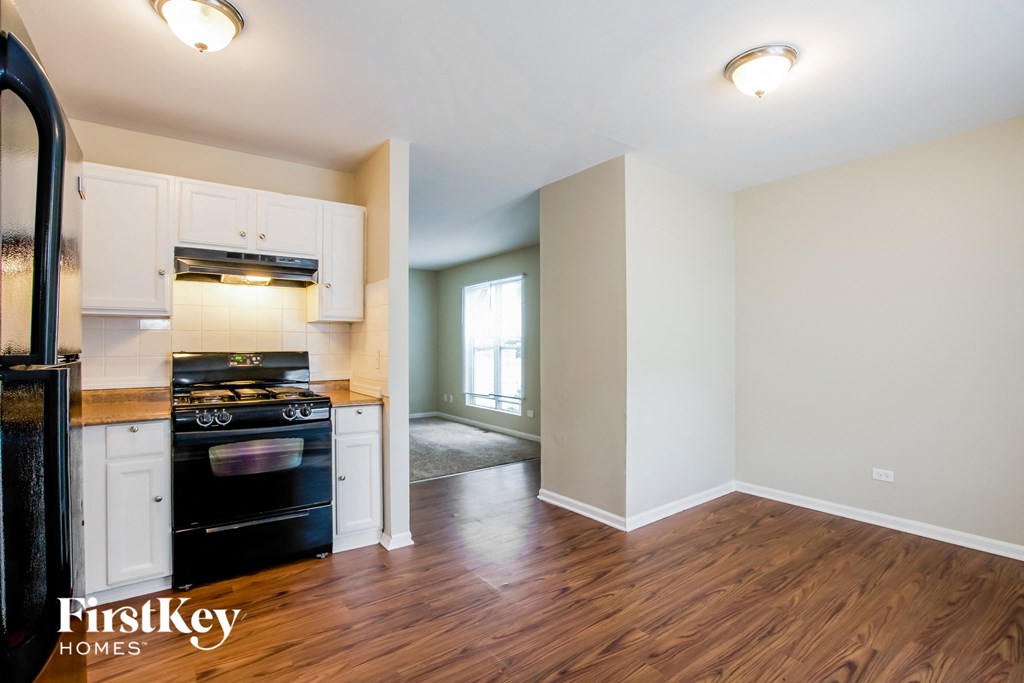 A kitchen with a stove top oven and a wooden floor.
