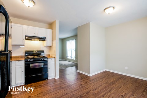 A kitchen with a stove top oven and a wooden floor.
