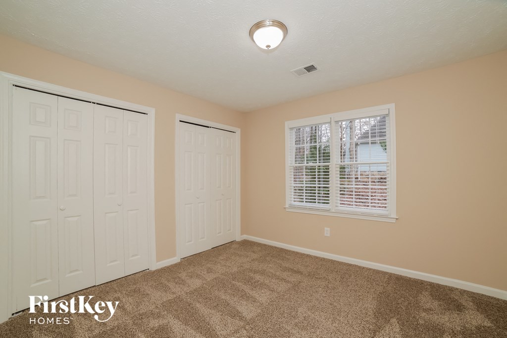 the master bedroom has two closets and a carpeted floor