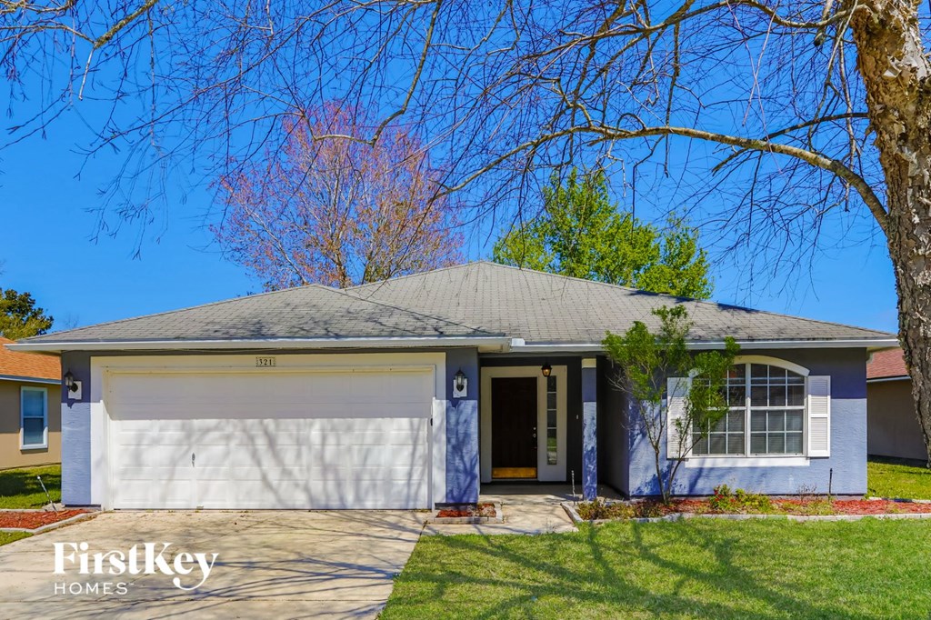 a white house with a white garage door and a tree