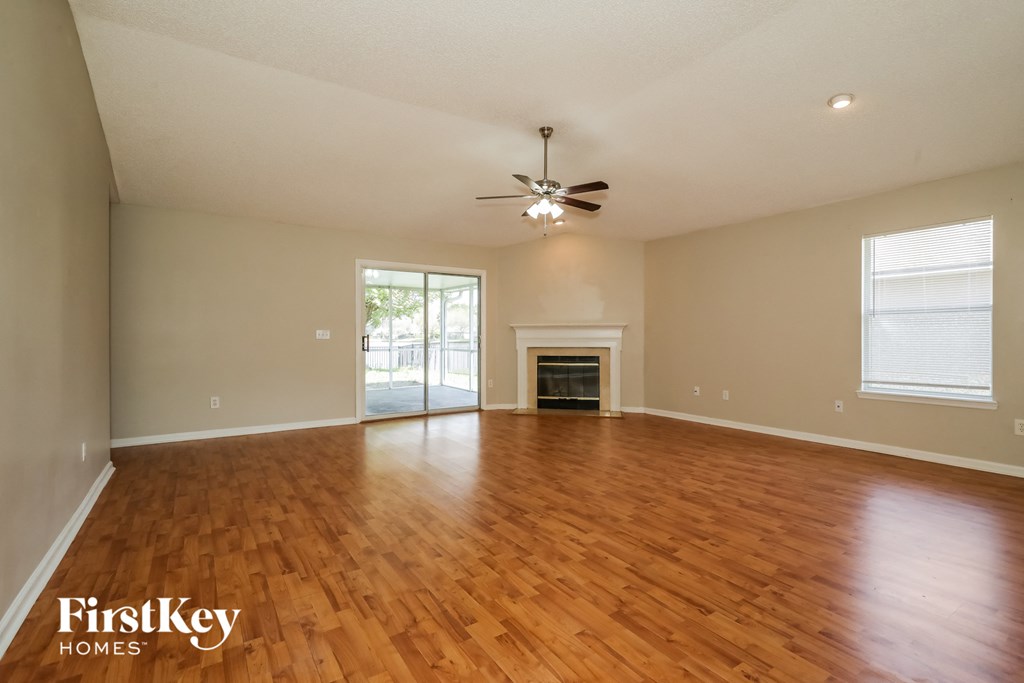 an empty living room with a ceiling fan and a fireplace