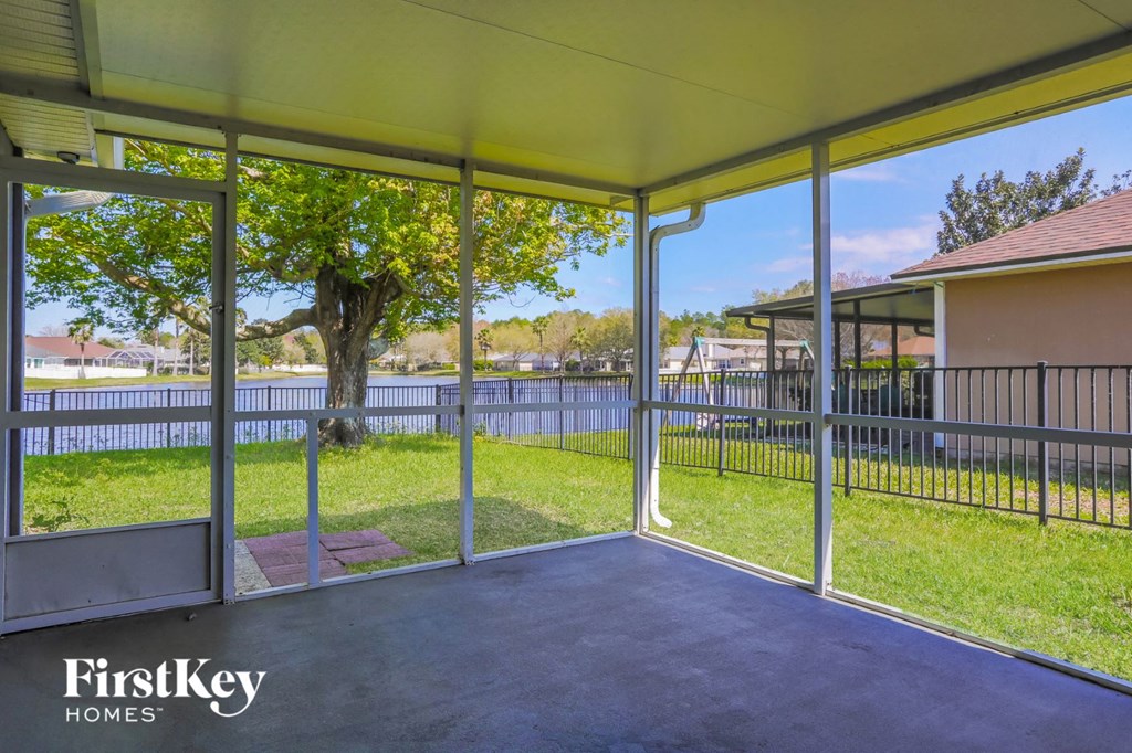 a patio area with glass doors and a fence and grass
