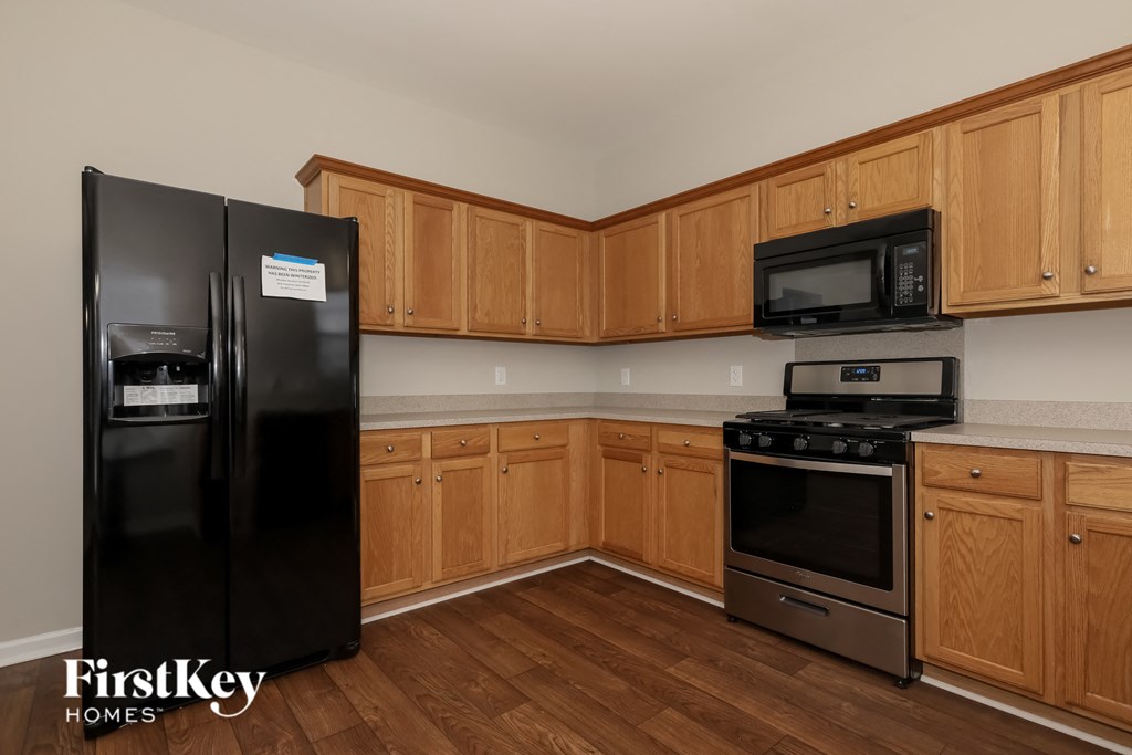 a kitchen with wooden cabinets and appliances and a black refrigerator