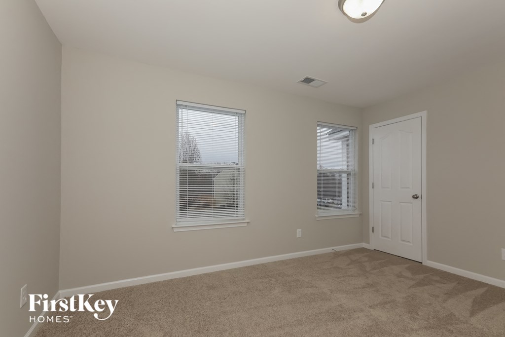 a bedroom with a carpeted floor and two windows