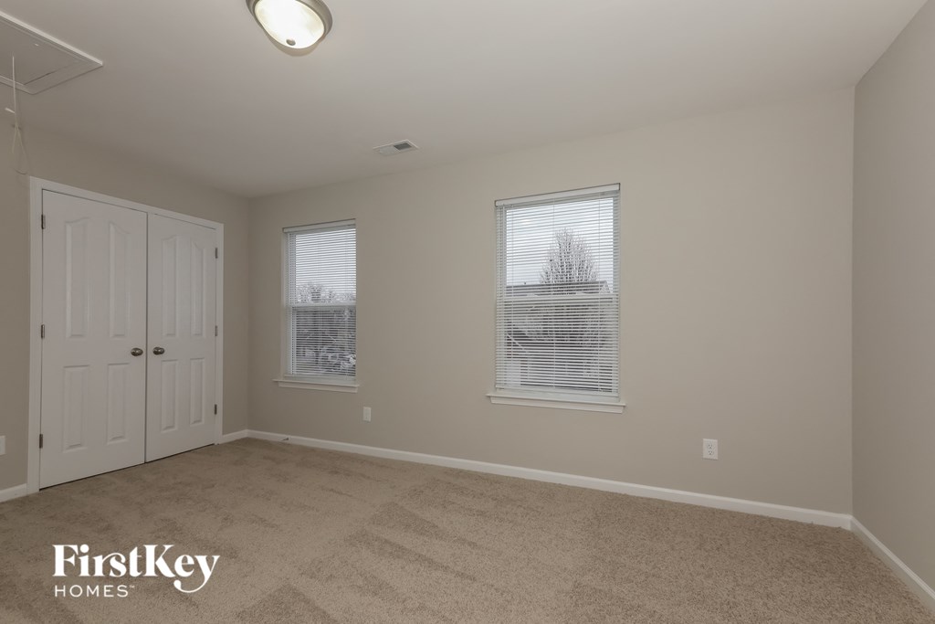a bedroom with a carpeted floor and two windows and a white door