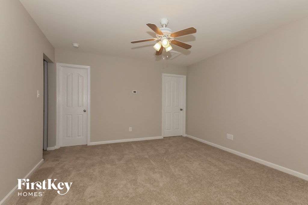 a empty room with a ceiling fan and two doors