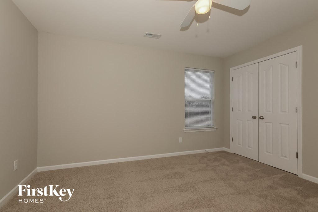 a bedroom with a carpeted floor and a ceiling fan