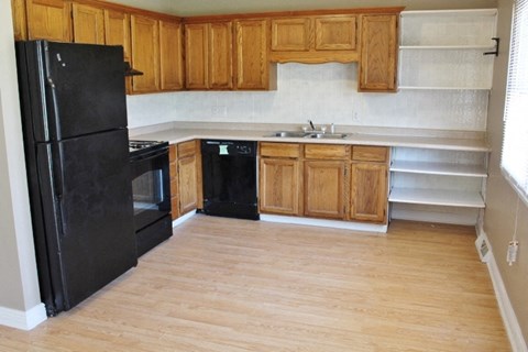 an empty kitchen with black appliances and wooden cabinets