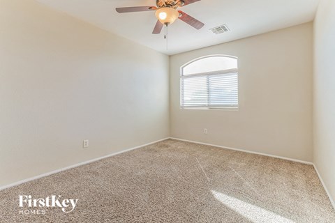the spacious living room with a ceiling fan and carpet