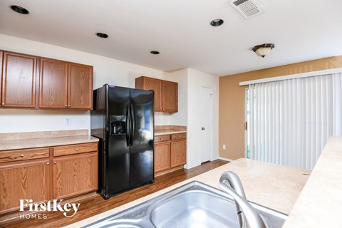 A kitchen with a black fridge and wooden cabinets.
