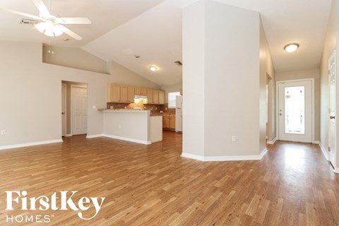 A spacious room with wooden floors and a ceiling fan.