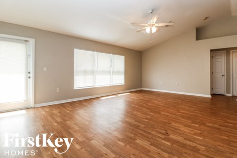 A spacious room with wooden floors and a ceiling fan.