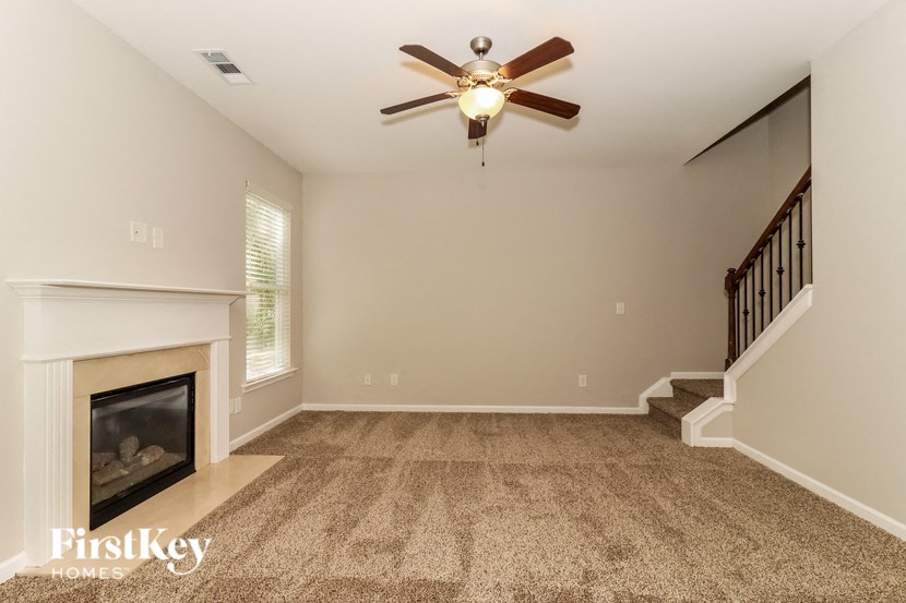 A spacious living room with a fireplace and a carpeted floor.