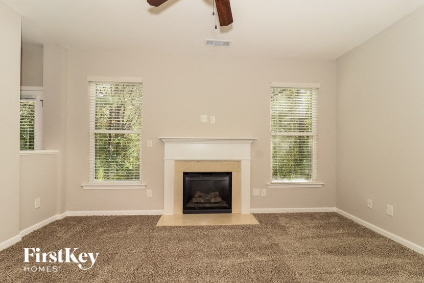 A living room with a fireplace and two windows.