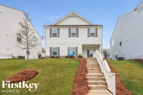 a white house with a staircase in front of a green lawn