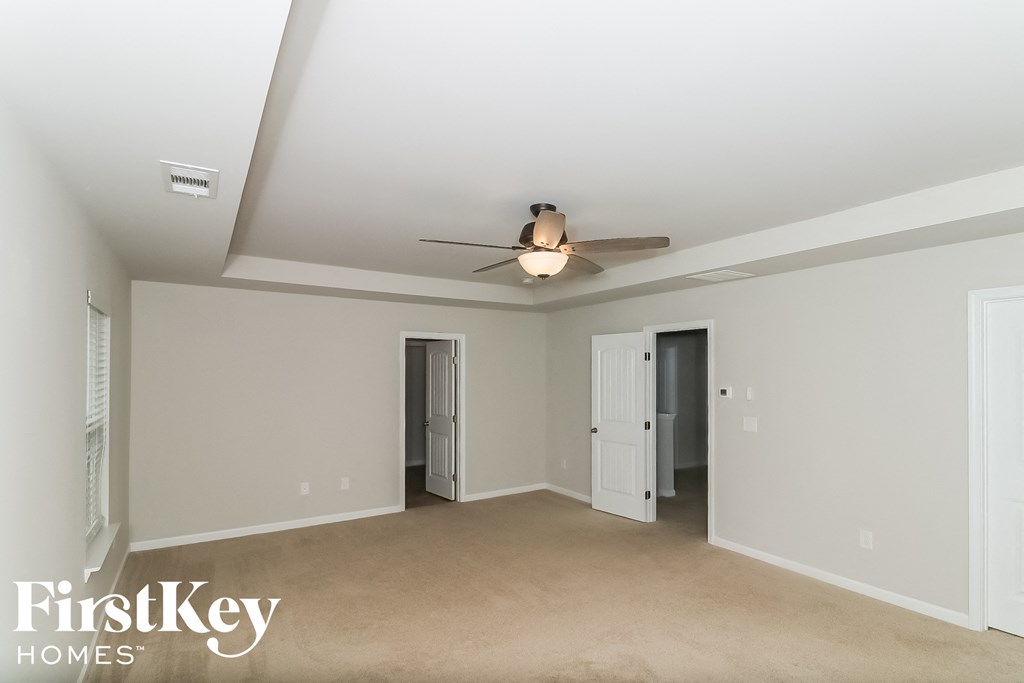 a living room with a ceiling fan and a door to a hallway