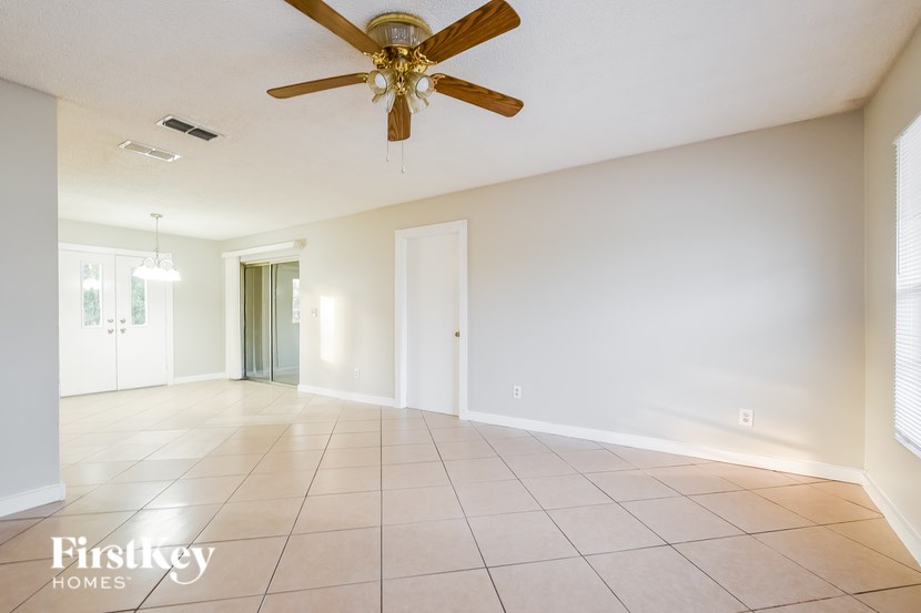 A spacious room with a ceiling fan and tiled flooring.