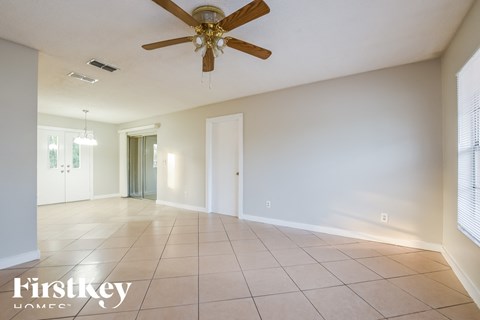 A spacious room with a ceiling fan and tiled floor.