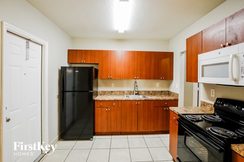 A kitchen with wooden cabinets and black appliances.