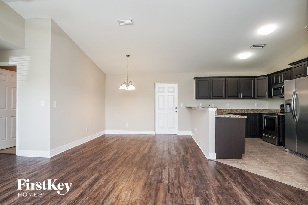the kitchen and living room of an empty house with wood flooring and black appliances