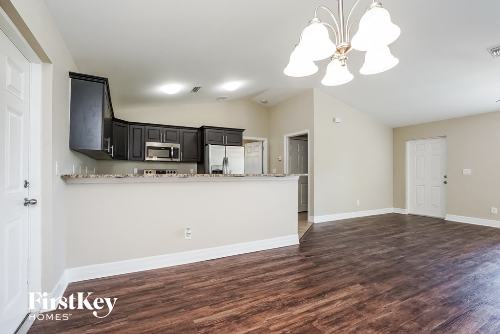 the living room and kitchen of an empty house with wood flooring