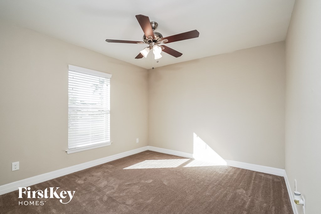 an empty room with a ceiling fan and a window