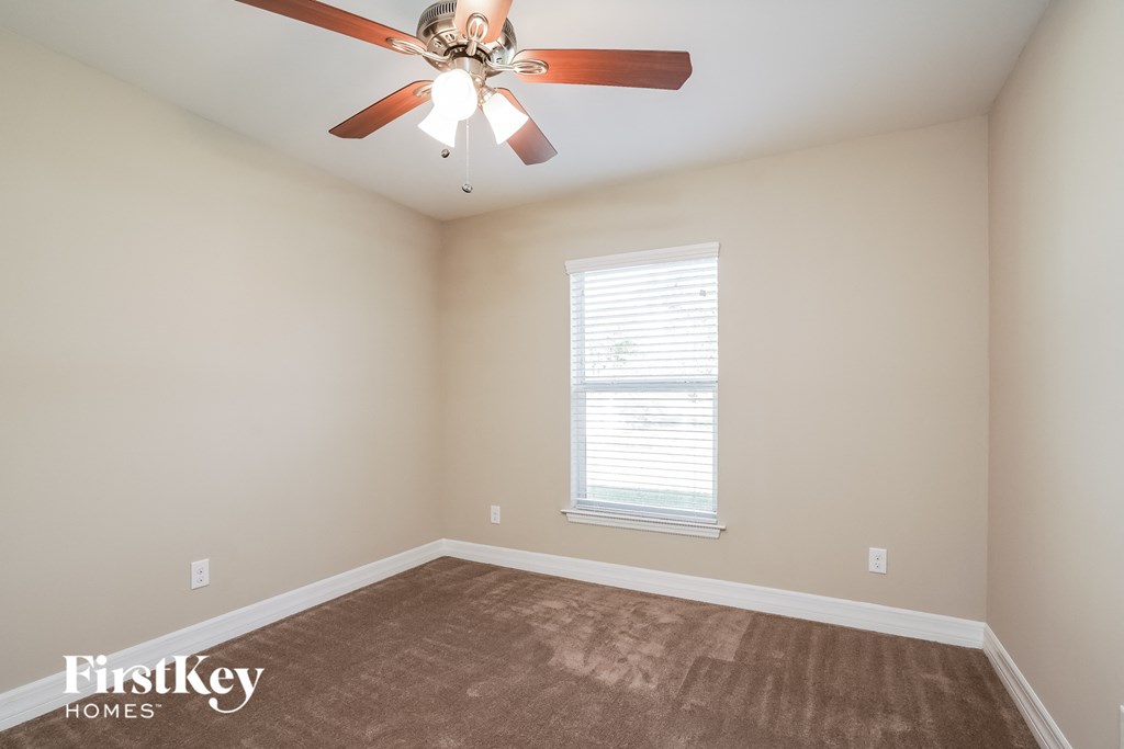 an empty room with a ceiling fan and a window