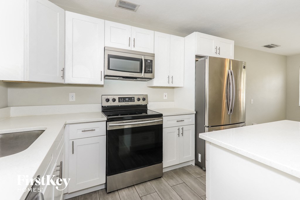 a white kitchen with stainless steel appliances and white cabinets