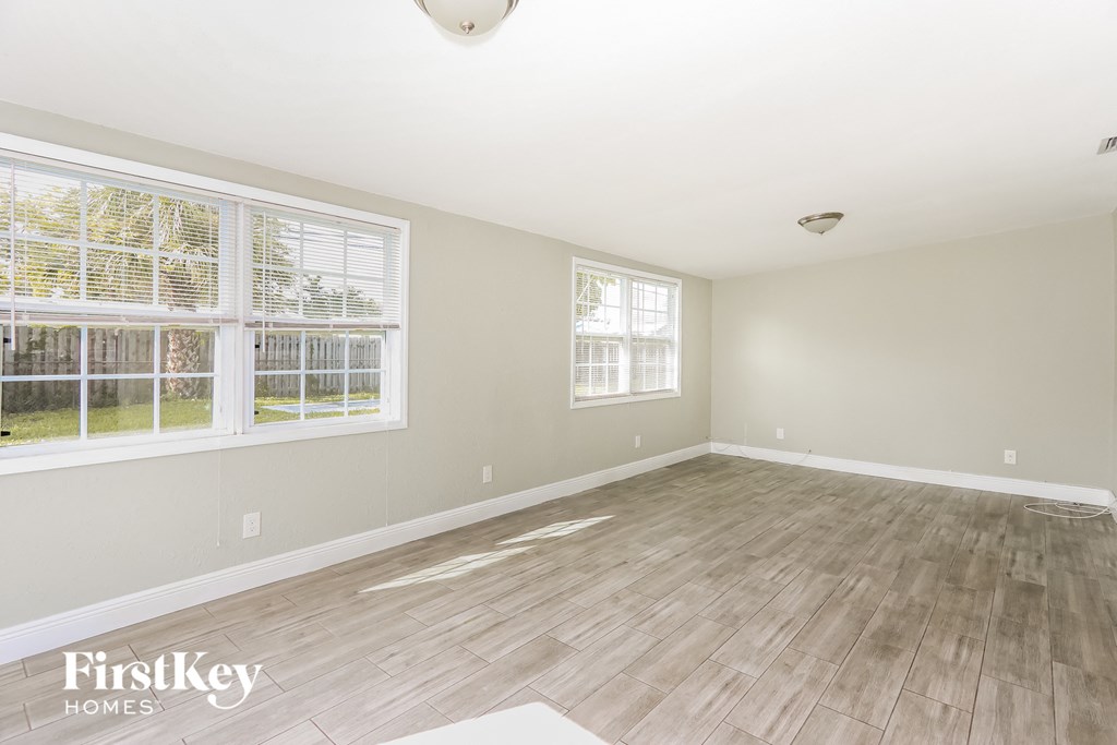 the living room of an empty house with wood floors and two windows