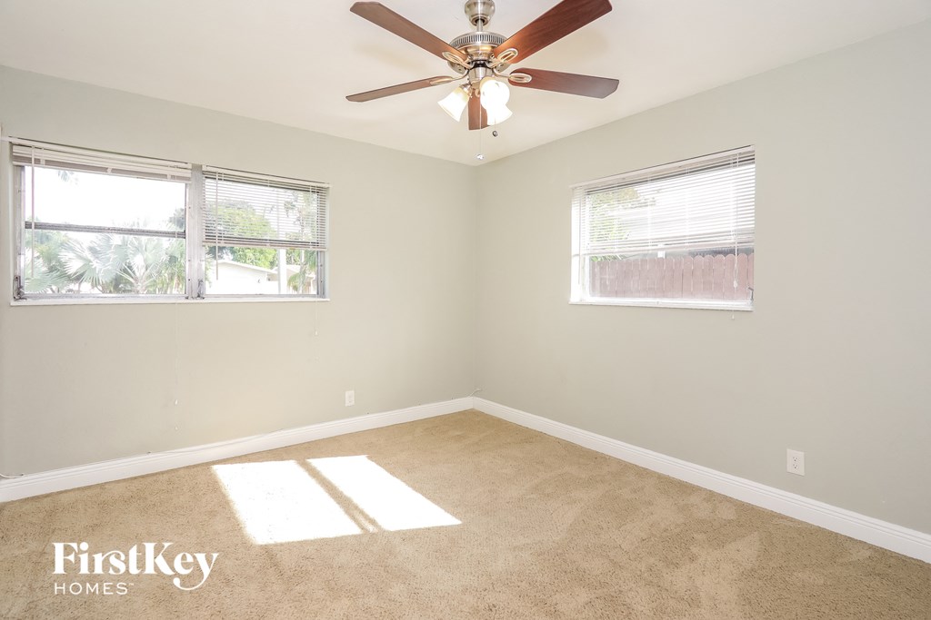 a bedroom with a ceiling fan and two windows