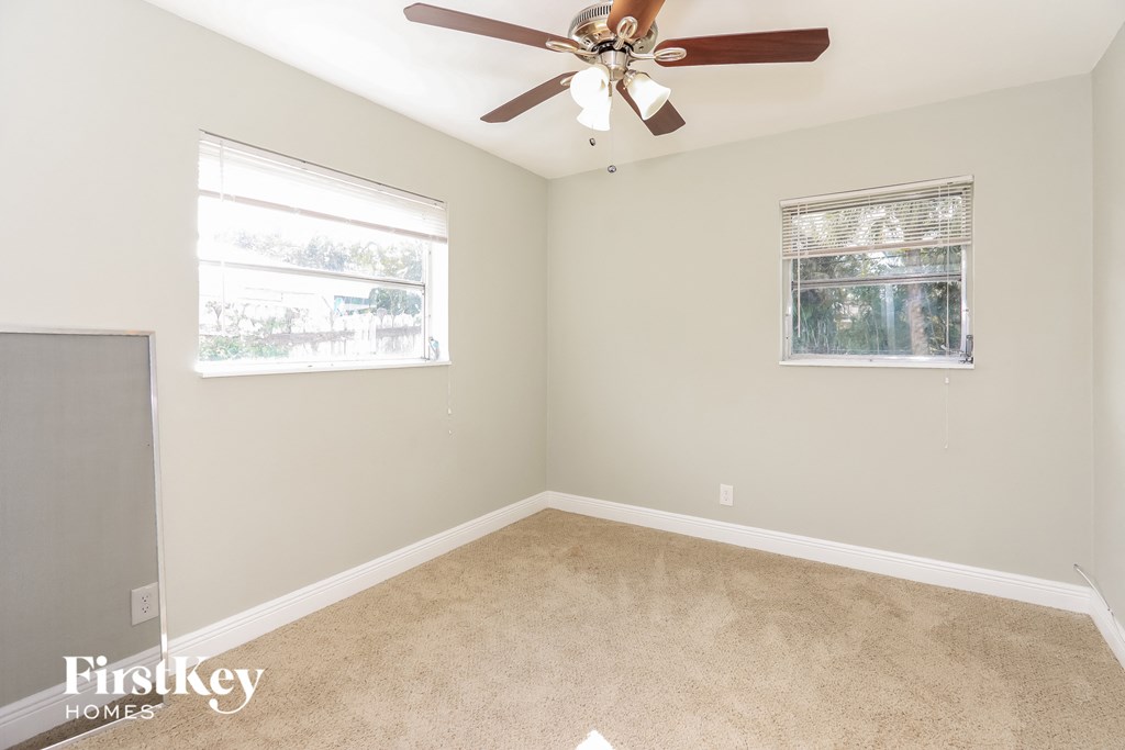 an empty room with a ceiling fan and a window