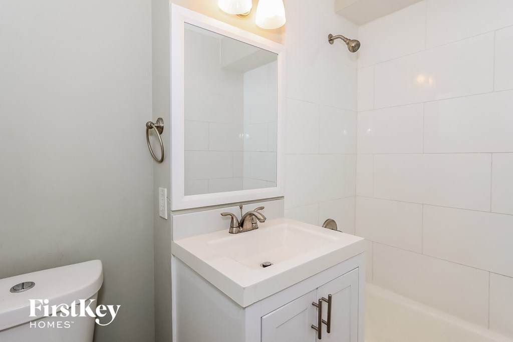 a white bathroom with a sink and mirror and a toilet