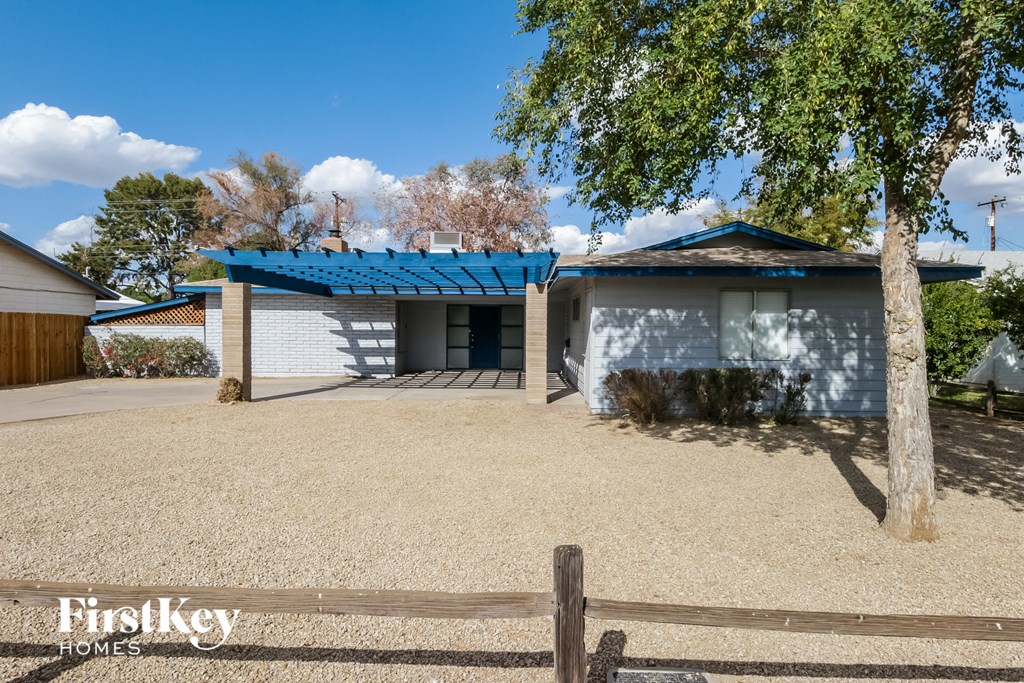a small white house with a blue roof and a wooden fence