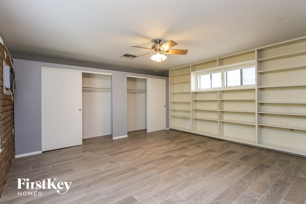 a walk in closet with shelves and a ceiling fan