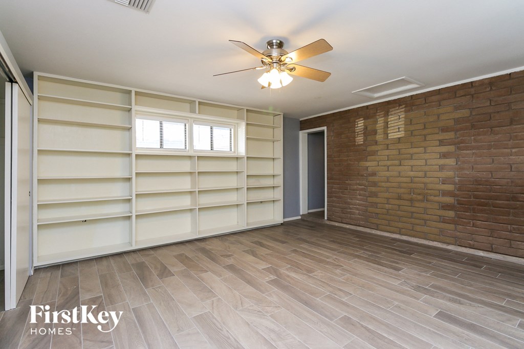an empty room with a brick wall and a ceiling fan