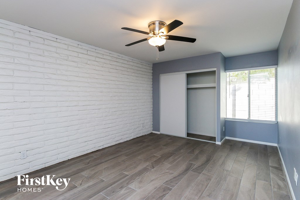 an empty room with a white brick wall and a ceiling fan