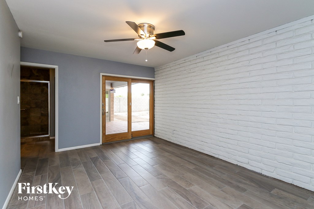 an empty living room with a white brick wall and a ceiling fan