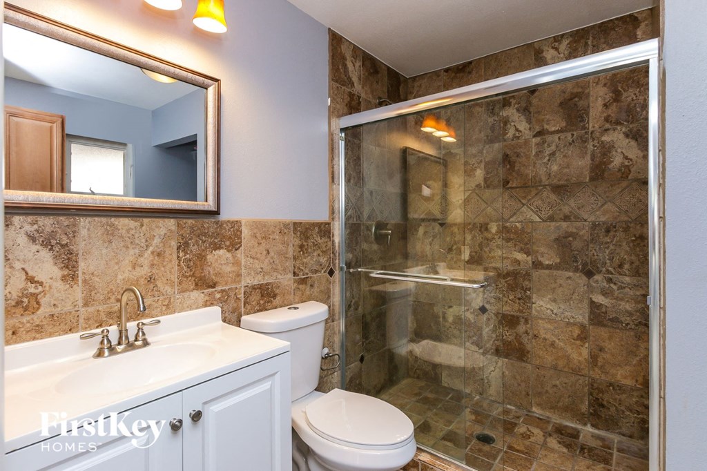 a bathroom with a shower toilet sink and a mirror