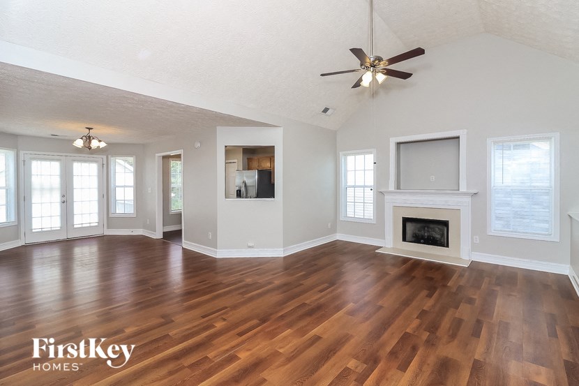 A spacious living room with wood flooring and a fireplace.