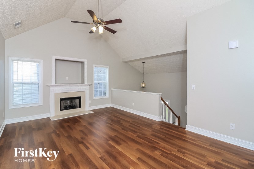 A spacious living room with wood flooring and a fireplace.