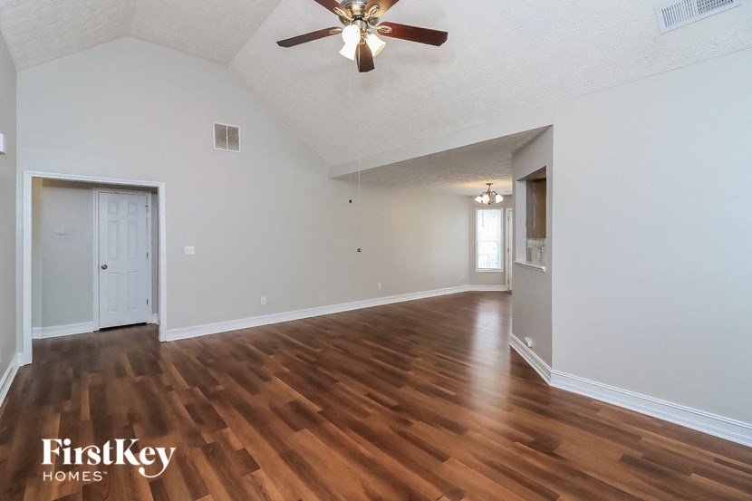A spacious room with wooden floors and a ceiling fan.