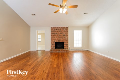 the living room with wood floors and a brick fireplace and a ceiling fan