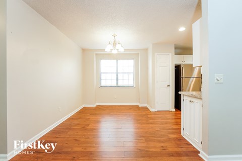 an empty living room with wood flooring and a kitchen