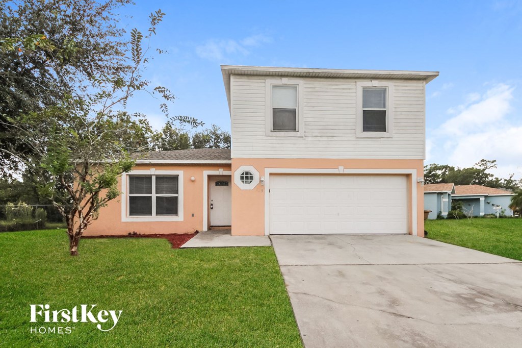 a pink and white house with a driveway and a garage door