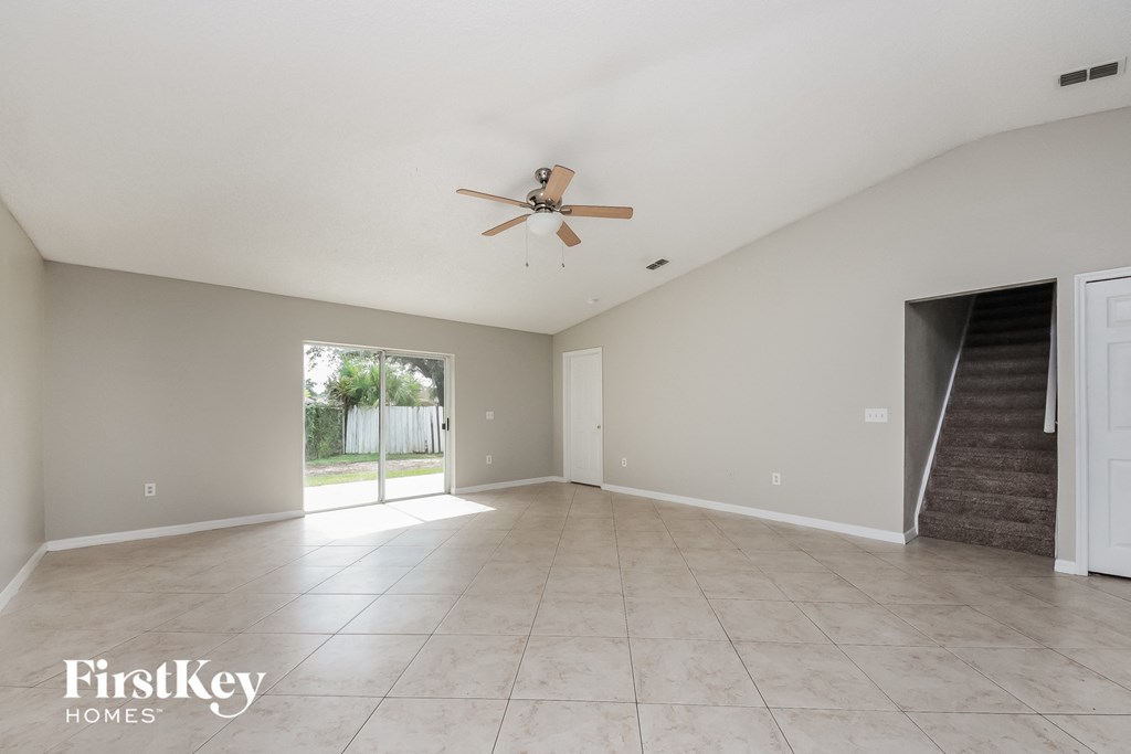 an empty living room with a ceiling fan and a door to a patio
