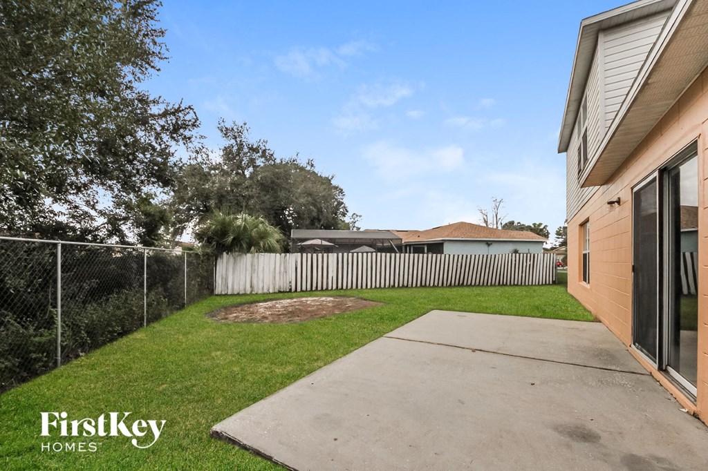 the backyard of a house with a fence and a yard with a concrete sidewalk