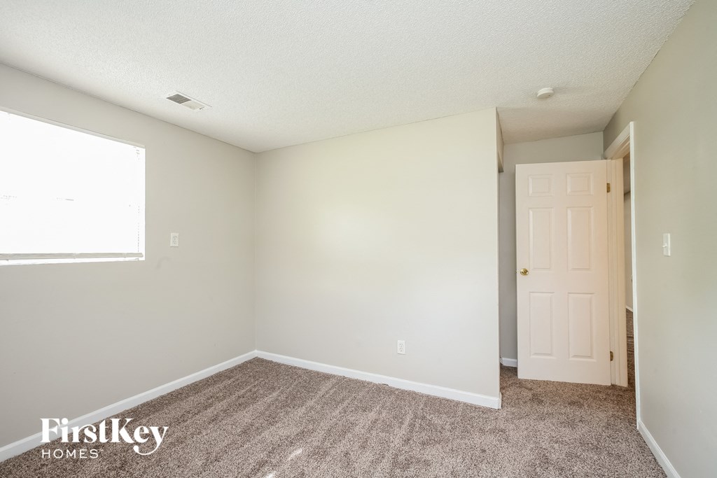 a bedroom with a door and a carpeted floor