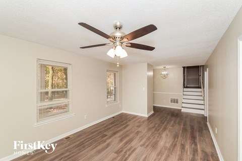 a living room with a ceiling fan and a staircase